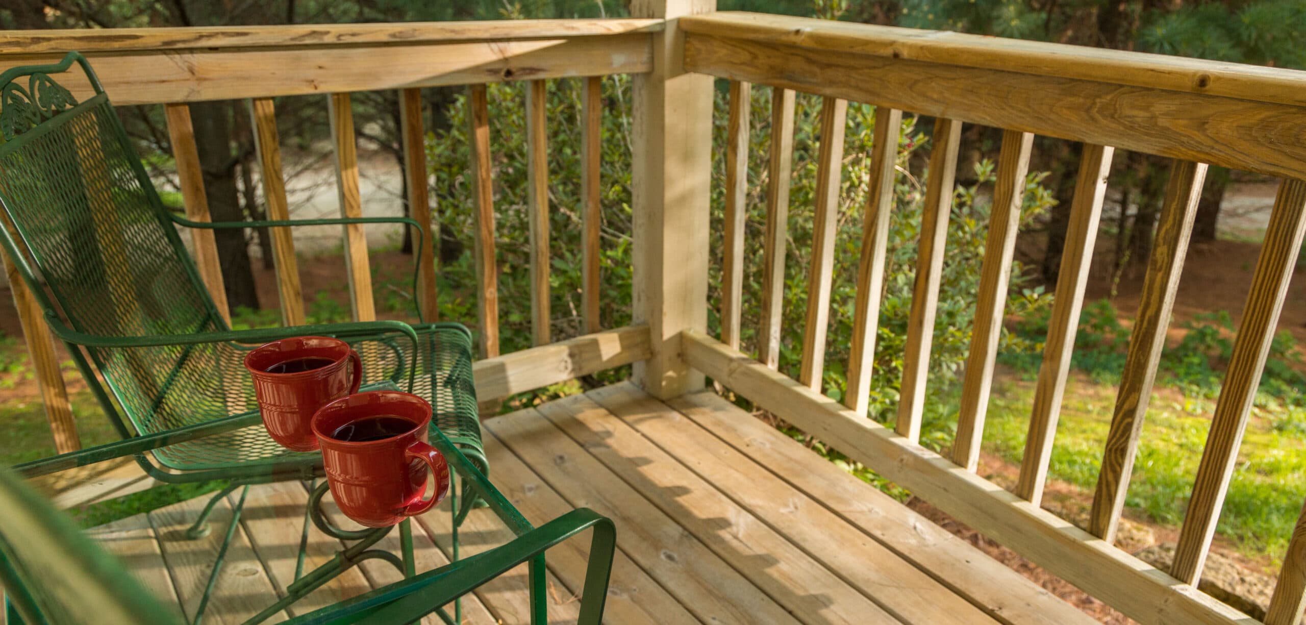 back deck with 2 green chairs and table with coffee cups
