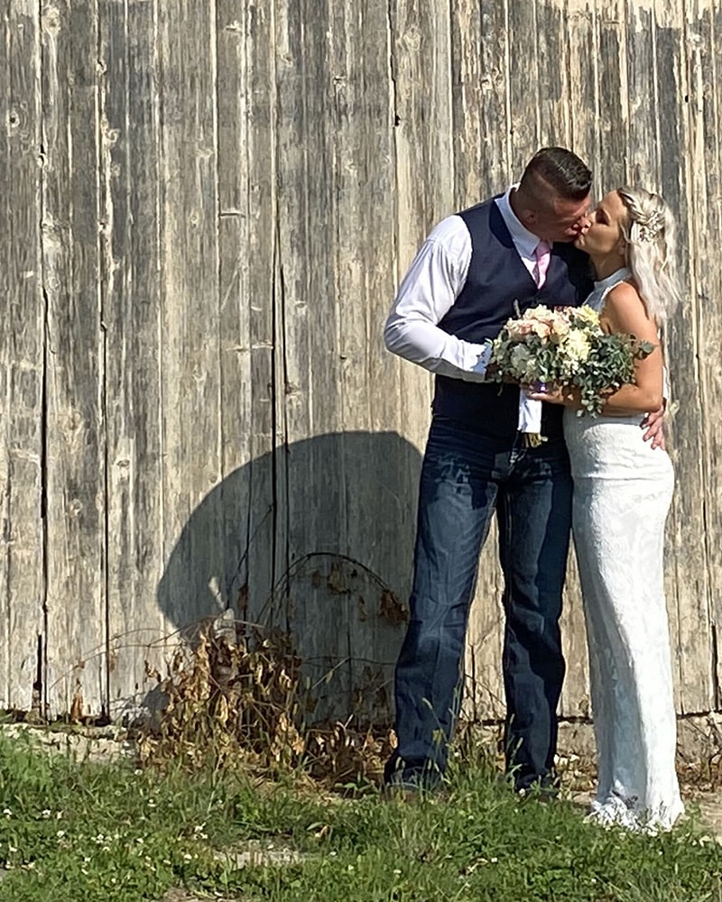 bride and groom kiss by barn