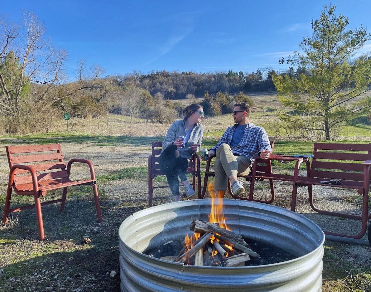 woman and man sitting by bonfire.