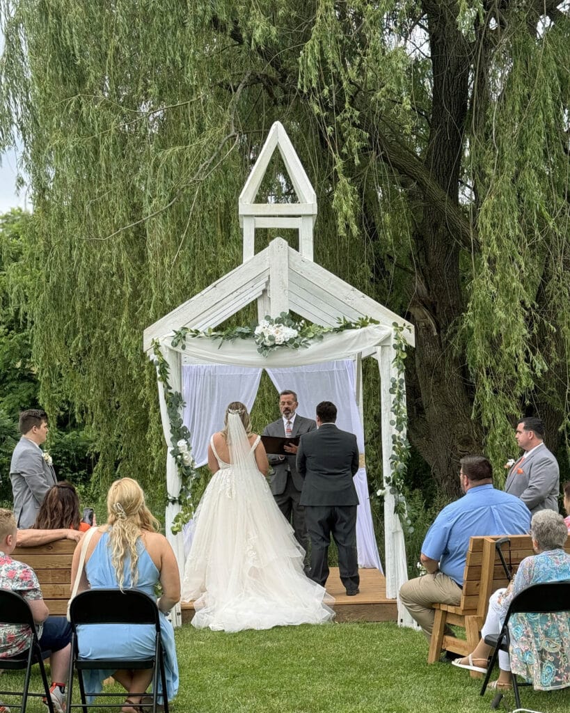 Couple getting married in rustic wedding arbor