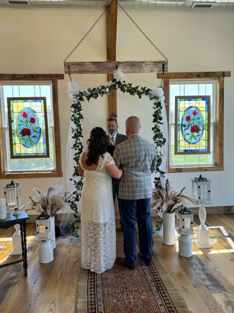 couple getting married under barn arch