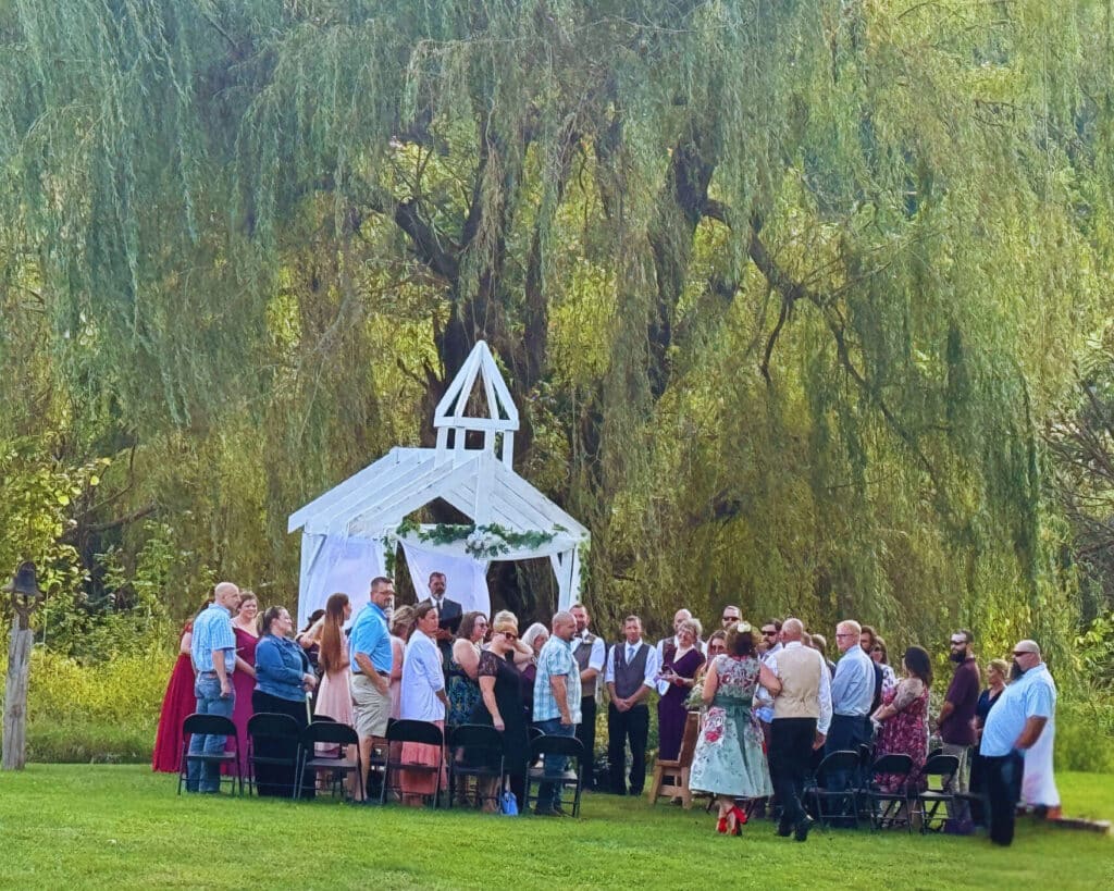 Bride walking down the aisle at outside rustic wedding arbor