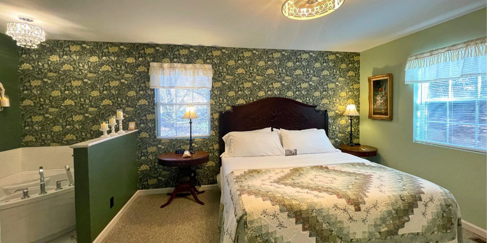 Large bed in room with green paint and wallpaper. jetted tub in alcove.