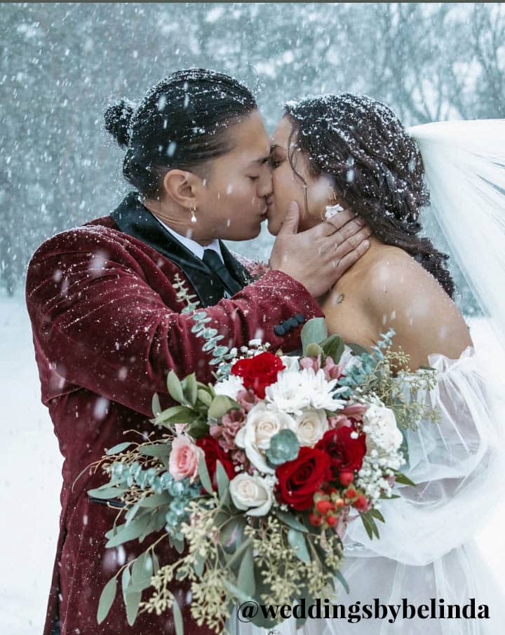 bride and groom in snow with text @weddingsbybelinda