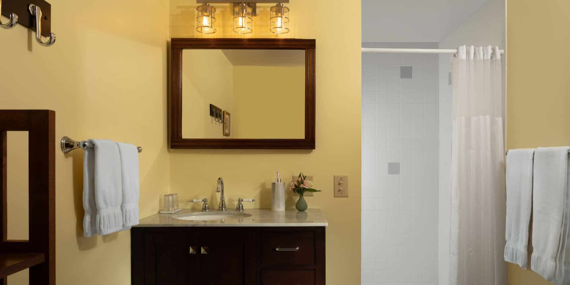 yellow bathroom with wood vanity and white tiled shower