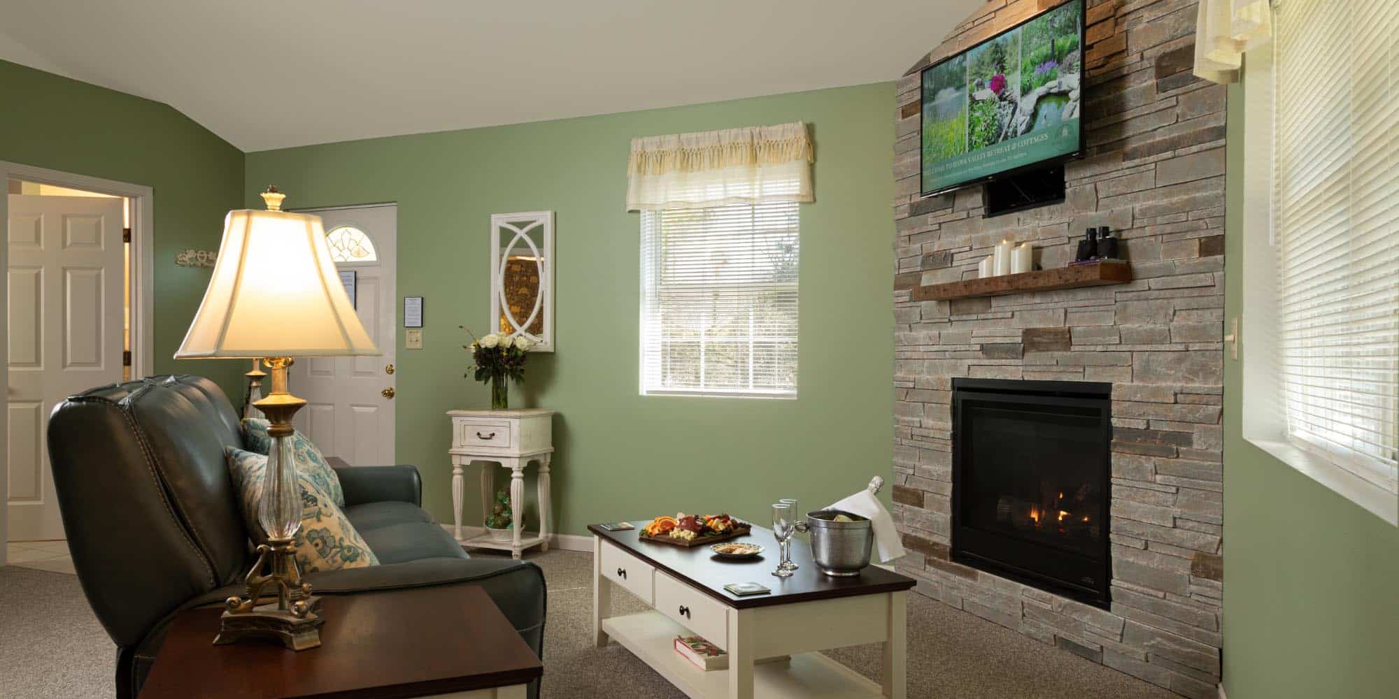 green walled room, stone fireplace, large couch and food set up on coffee table.