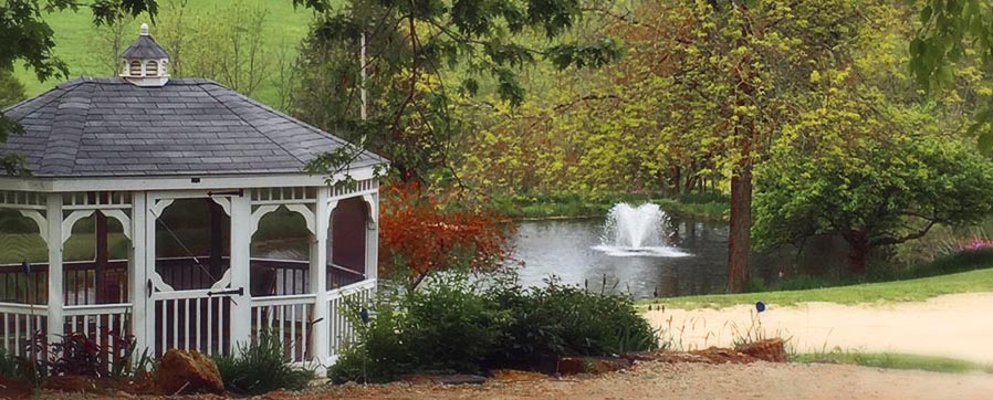 Gazebo with pond fountain in back with fall changing leaves