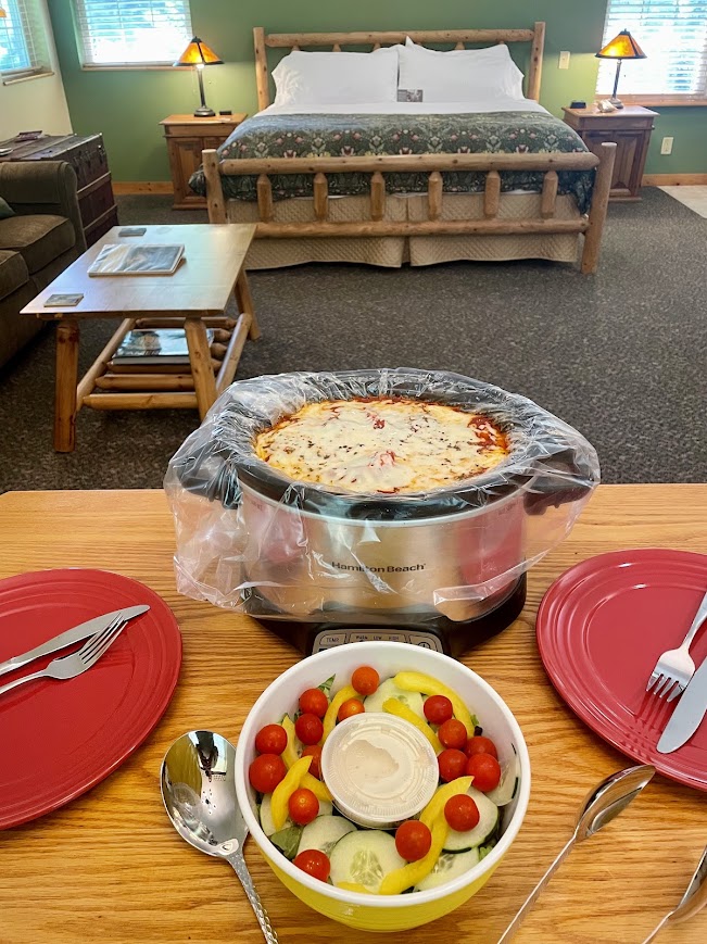 Veggie lasagna in a crock pot and a salad in bowl all set in the Pines cottage